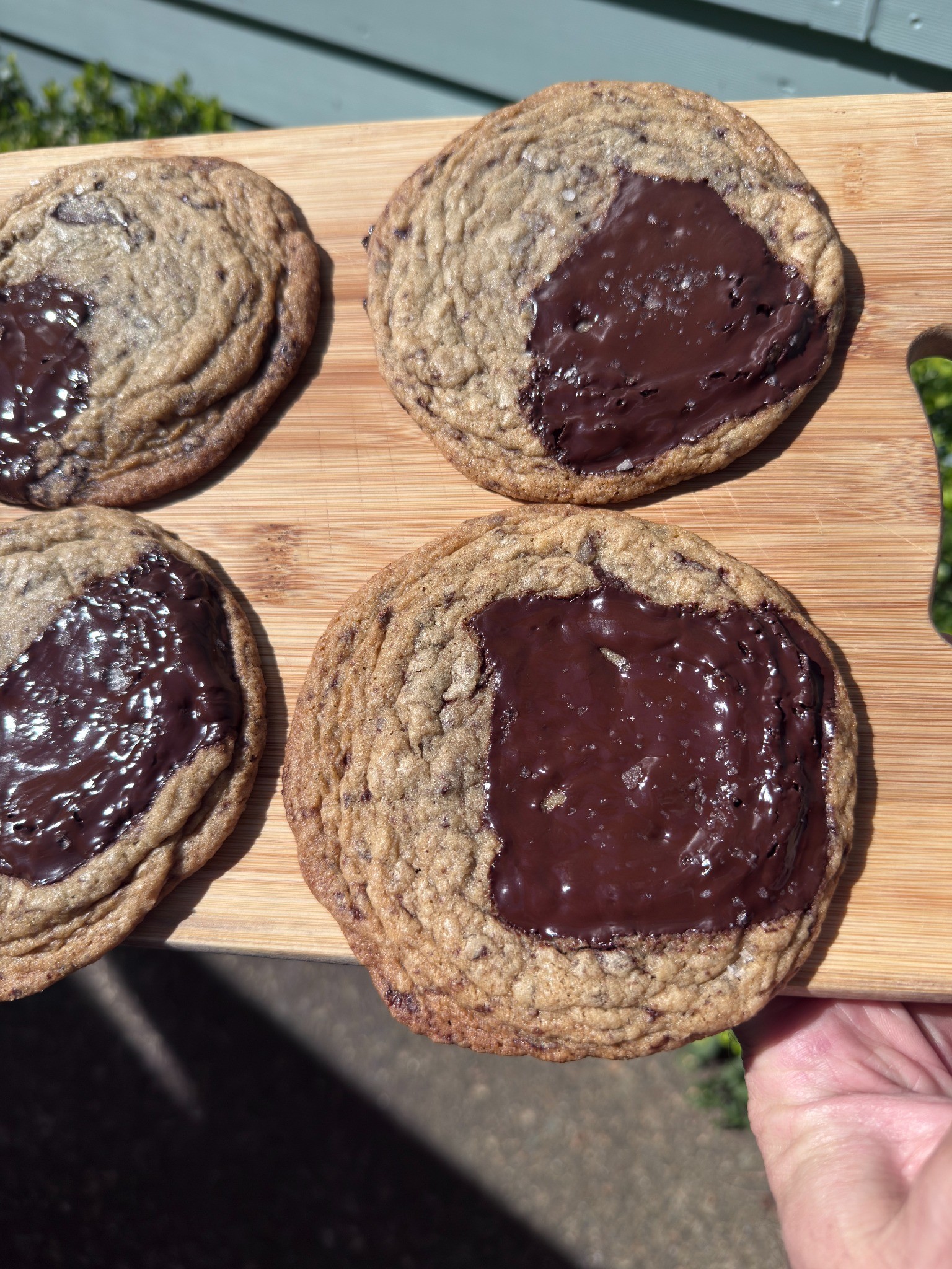 Four handmade chocolate cookies on a wooden board outdoors